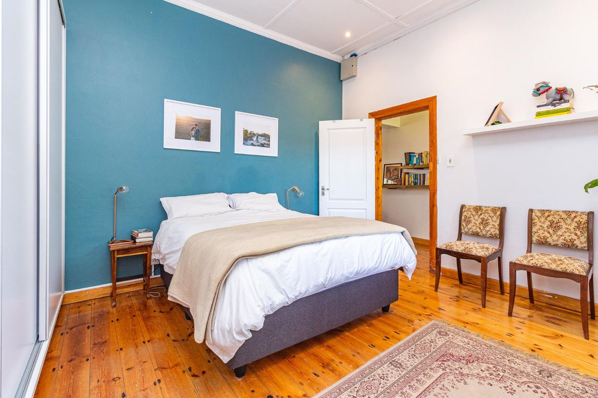 A well-maintained bedroom featuring polished timber flooring, a bold blue accent wall, and built-in wardrobe storage.