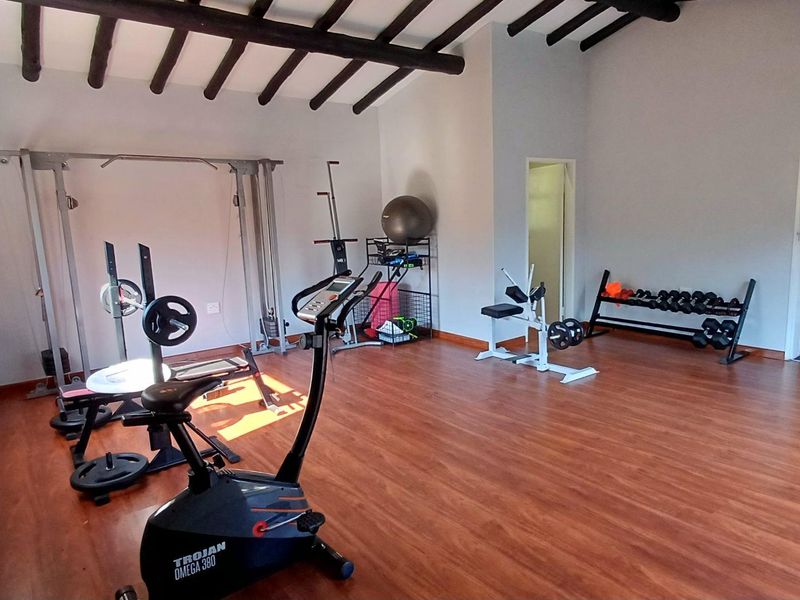 A dedicated home gym space featuring exposed timber ceiling beams and durable laminate flooring, providing a functional area for fitness activities.