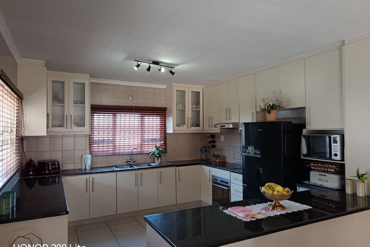 A well-maintained kitchen featuring cream cabinetry, dark granite countertops, tiled backsplash, and integrated appliances, offering a functional and clean workspace.