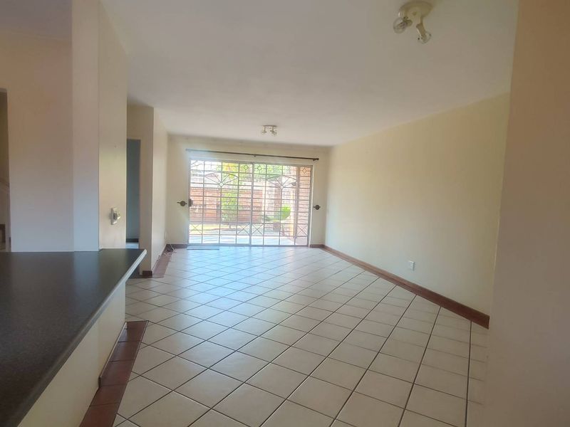Spacious open-plan living area featuring tiled flooring, a breakfast bar, and a sliding glass door leading to the exterior.