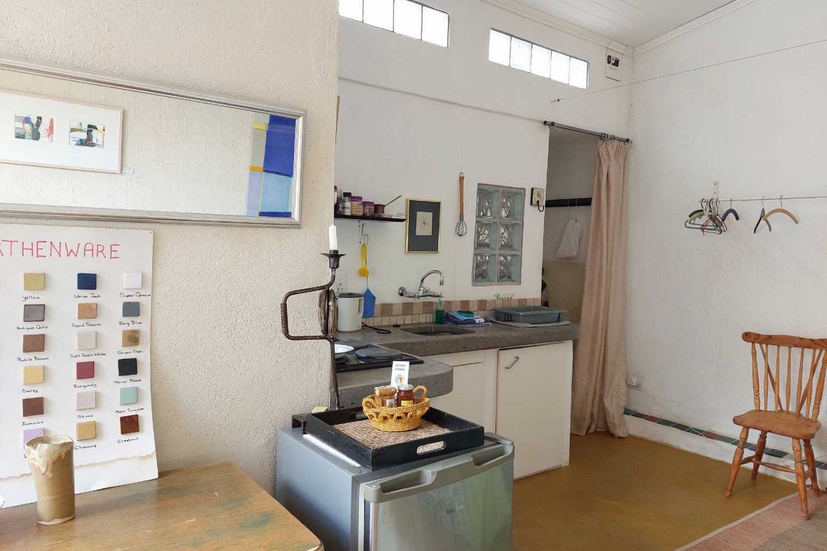 A compact kitchen area featuring basic cabinetry, a sink, and clerestory windows, providing a functional prep space within a larger room.