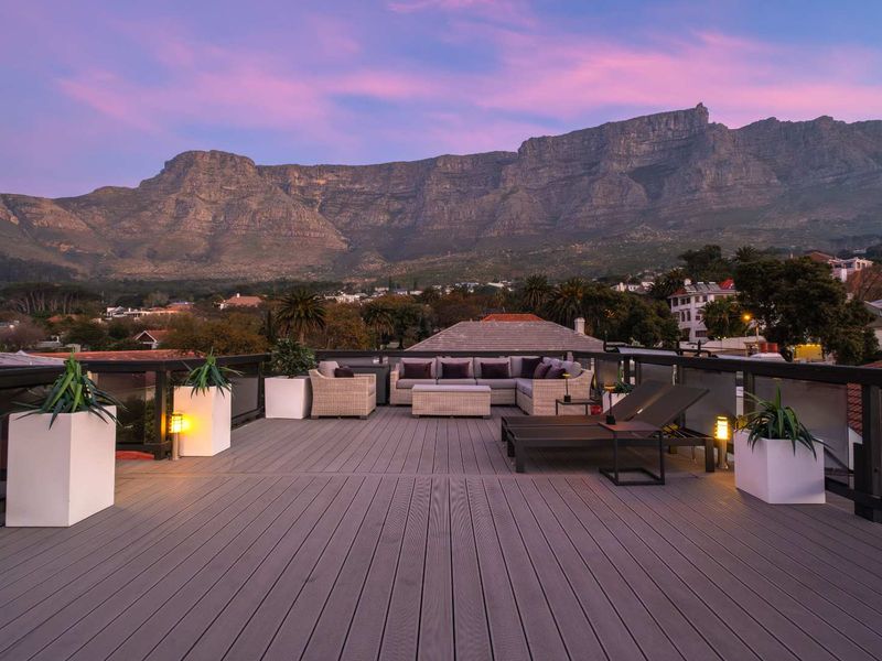 Spacious rooftop terrace featuring composite decking and glass balustrades, offering panoramic mountain views.