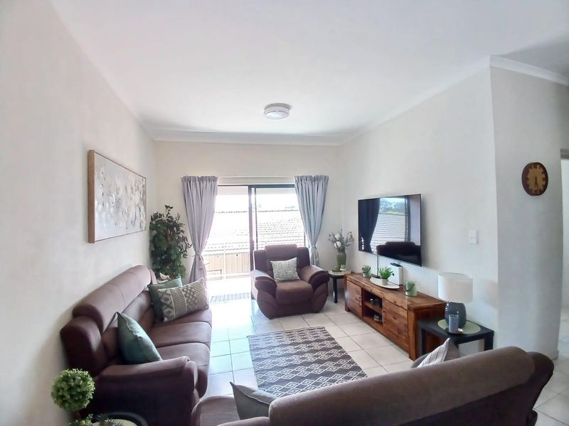 A well-maintained living room featuring tiled flooring and a sliding glass door that provides access to an outdoor area.