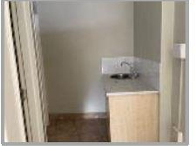 A small utility space featuring a built-in sink with cabinetry and a tiled splashback, suitable for a kitchenette or wash area.