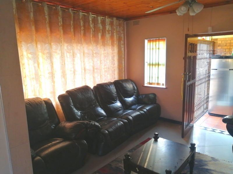 A living room featuring tiled flooring, a timber ceiling, and a ceiling fan, with direct access to an exterior area through a security gate.