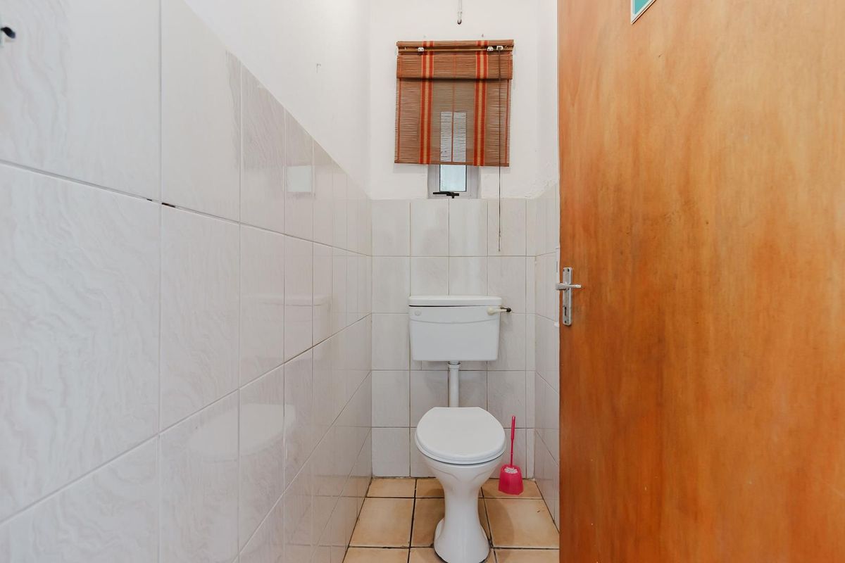 A compact, functional bathroom featuring tiled walls and flooring, equipped with a standard toilet and wooden door access.