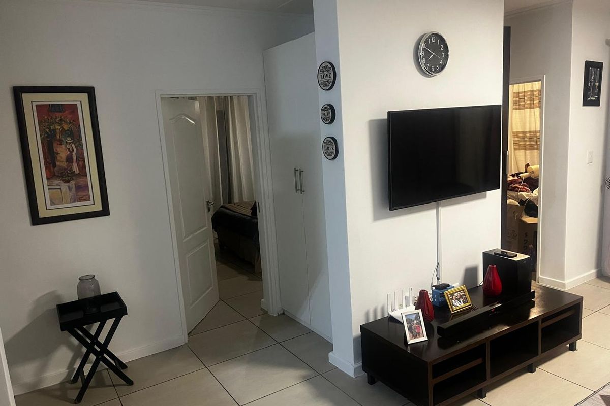 A view of an interior living area featuring tiled flooring, a built-in cupboard, and access to an adjacent bedroom.
