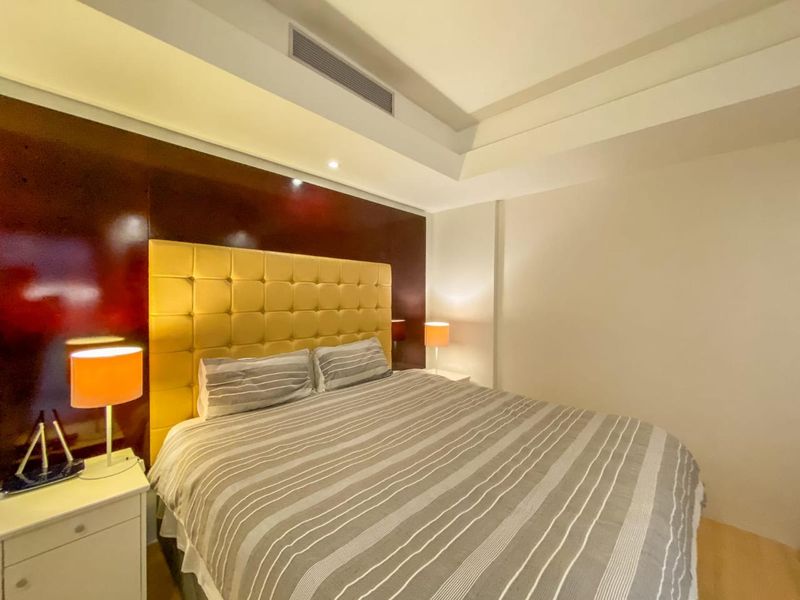 A well-maintained bedroom featuring a recessed ceiling with integrated lighting, ducted air conditioning, and light-toned laminate flooring.