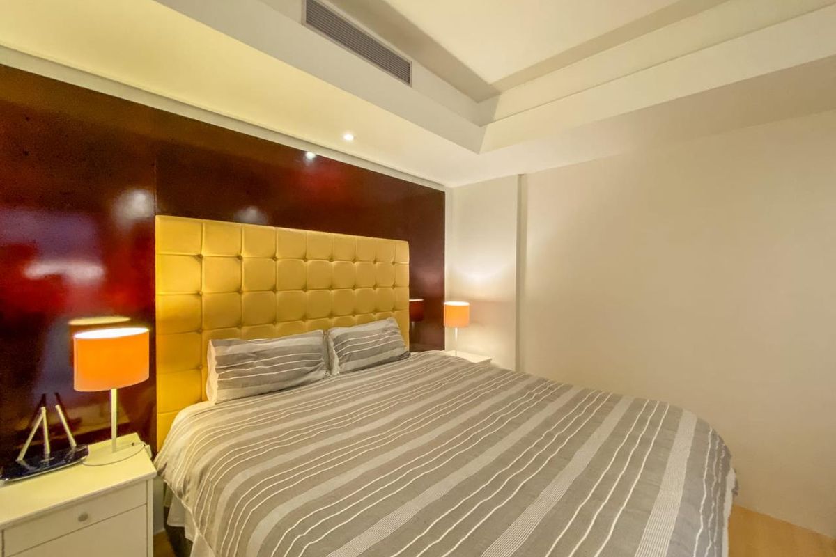A well-maintained bedroom featuring a recessed ceiling with integrated lighting, ducted air conditioning, and light-toned laminate flooring.