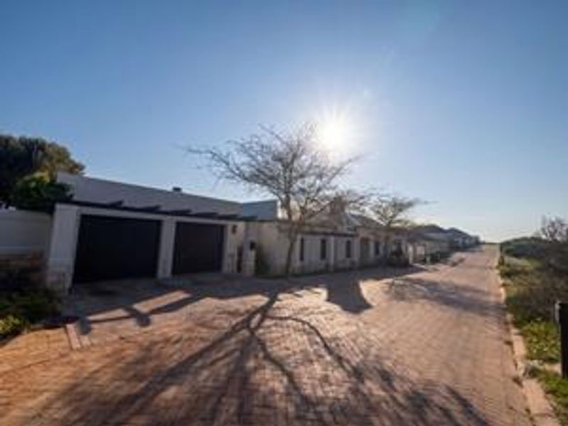 Front exterior view of the property featuring a paved driveway, double garage, and boundary wall under a clear sky.