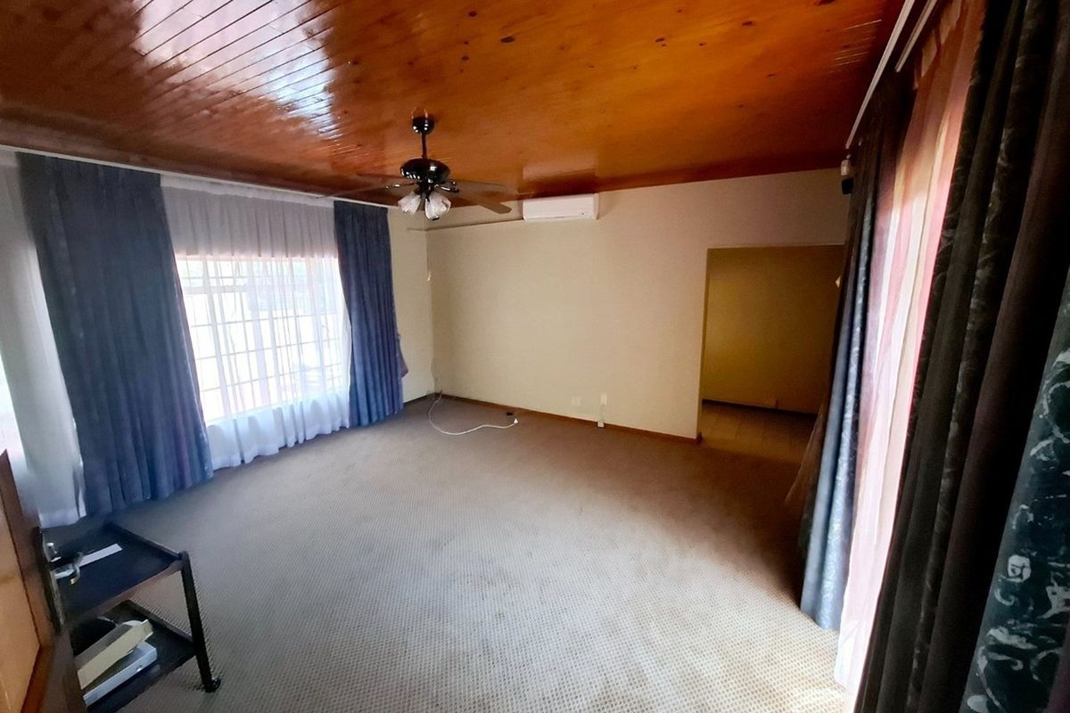 Spacious living area featuring a timber-paneled ceiling, ceiling fan, and split-system air conditioning, offering a neutral canvas for personalization.