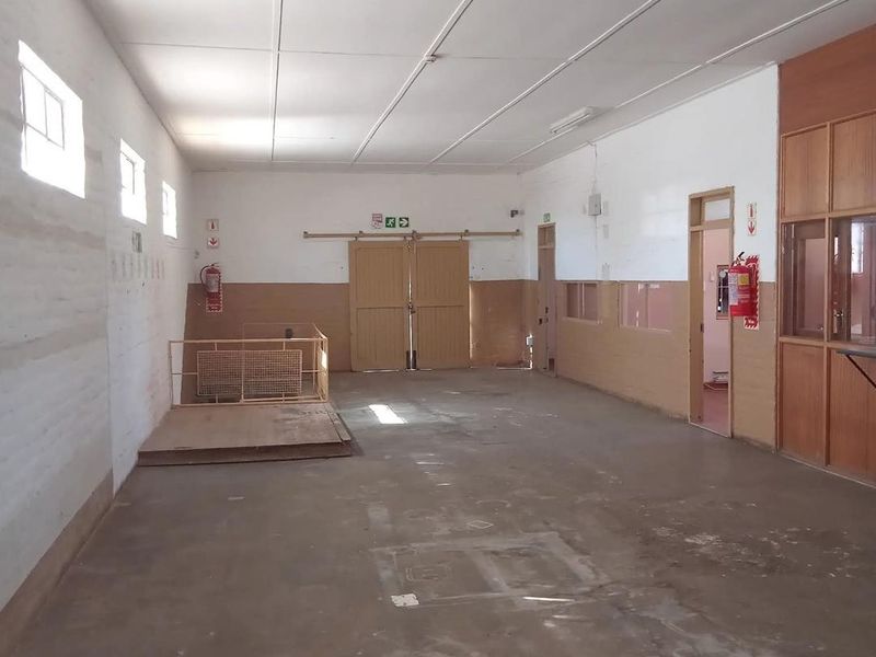 Spacious industrial utility area featuring concrete flooring, a raised platform with safety railing, sliding doors, and integrated office partitioning.