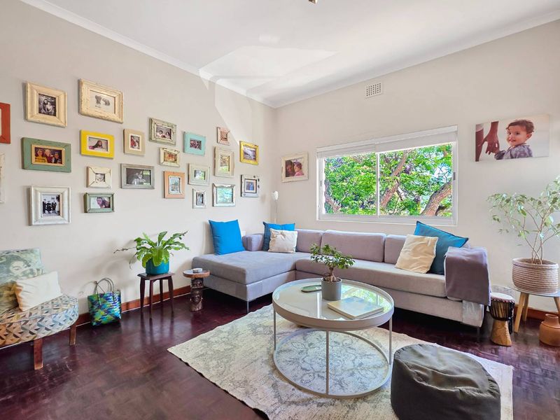 A bright and inviting living room featuring warm parquet flooring, a large sliding window, and classic cornice detailing.