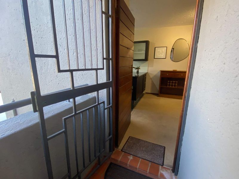 Entrance area featuring a secure metal gate, solid timber door, and tiled threshold leading into the interior living space.