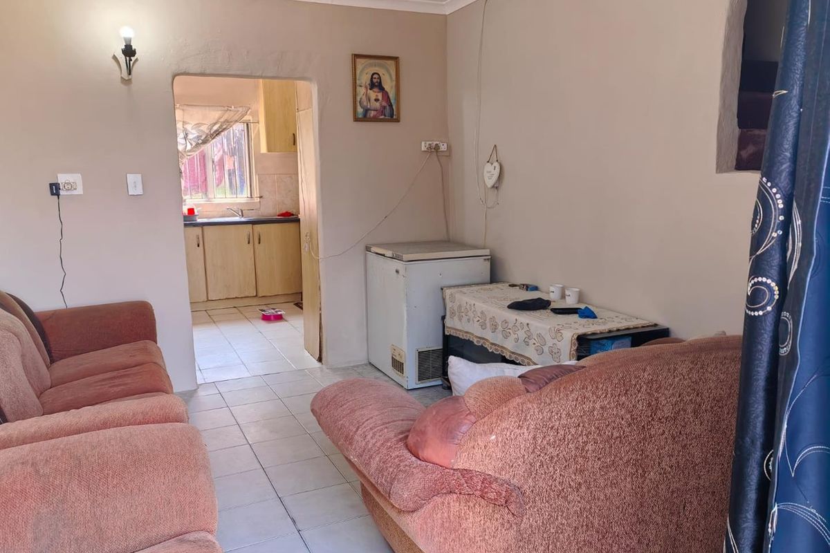 A living room area with tiled flooring and coved ceilings, featuring an open transition to the adjacent kitchen space.
