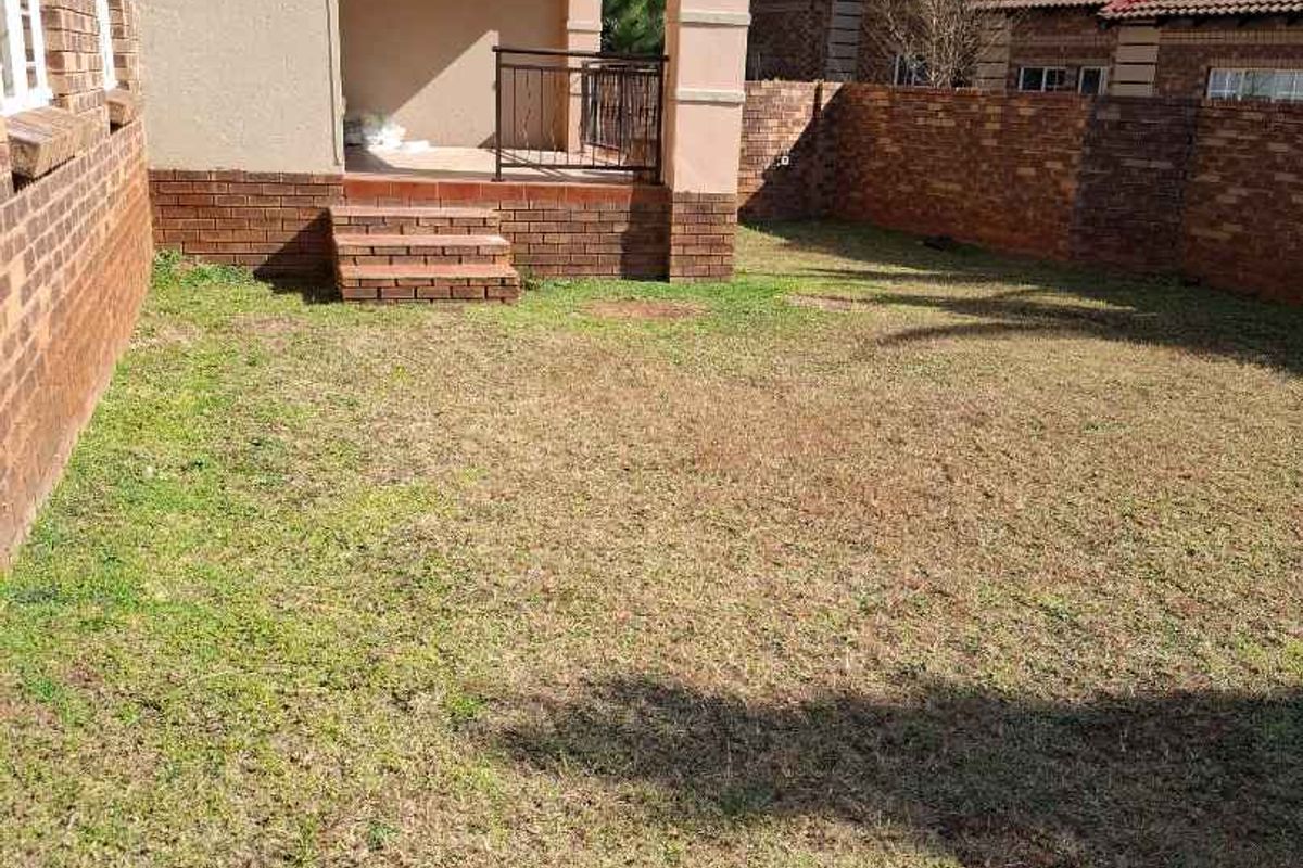 A private rear garden featuring a paved patio area with brick steps and a perimeter brick wall, offering a low-maintenance outdoor space.