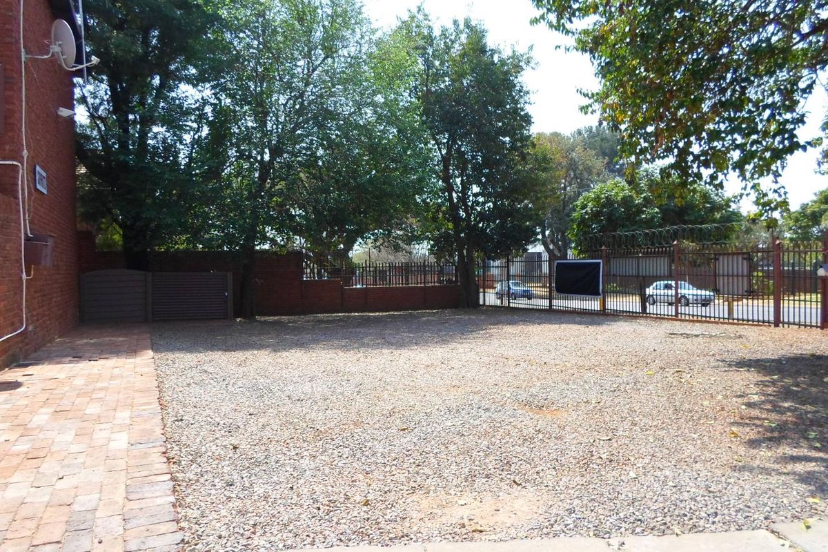 A spacious outdoor area featuring a gravel surface, brick paving, and secure perimeter fencing with razor wire.