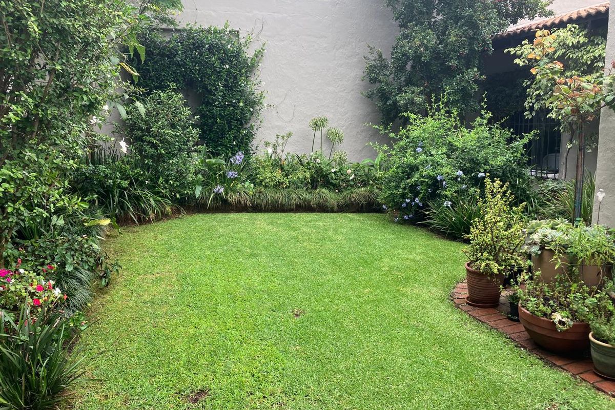 A private rear garden featuring a well-maintained lawn, established perimeter landscaping, and a solid boundary wall, providing a peaceful outdoor space.