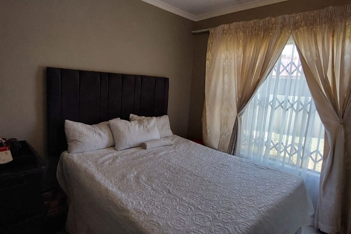 A standard bedroom featuring a window with security gate and curtain tracks.