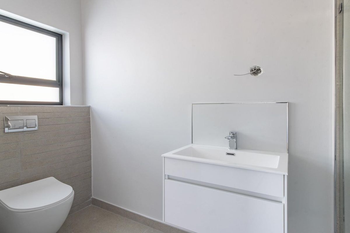 Modern bathroom featuring a wall-hung vanity, a sleek wall-mounted toilet with a concealed cistern, and a glass shower enclosure.