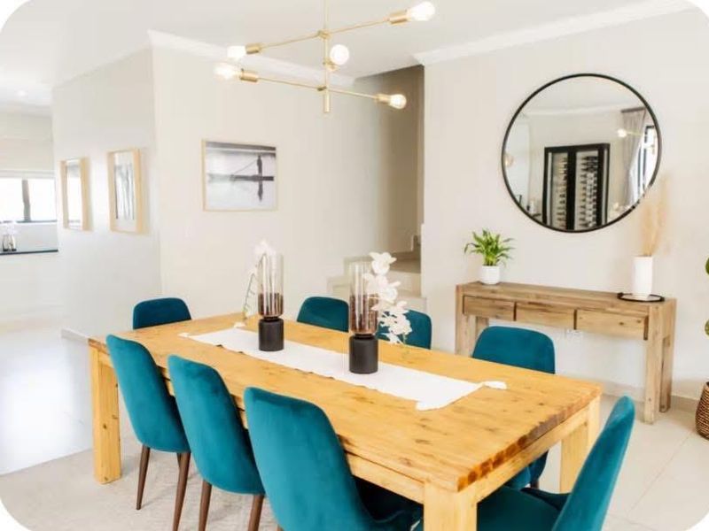 A bright and well-maintained dining area featuring modern lighting, neutral walls, and tiled flooring, seamlessly connected to the adjacent living space.