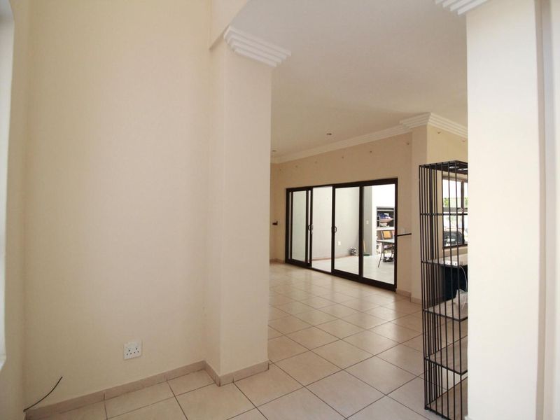 Spacious open-plan living area featuring neutral tiled flooring, decorative crown molding, and large sliding glass doors that provide ample natural light.