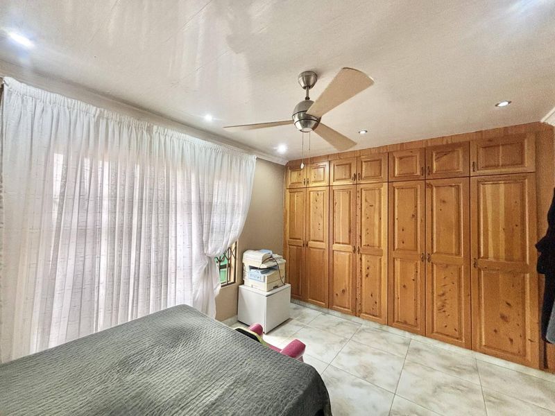 Bedroom featuring extensive built-in wooden cabinetry, tiled flooring, a ceiling fan, and recessed lighting.