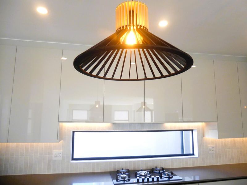 Modern kitchen featuring high-gloss cabinetry, a built-in gas hob, under-cabinet lighting, and a sleek horizontal window splashback.