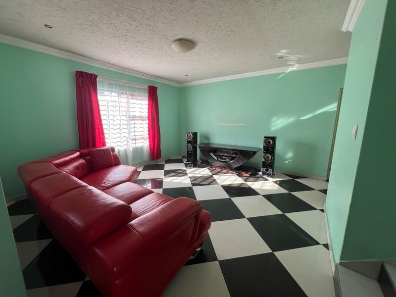 A living room featuring a distinctive checkered tile floor, coved cornicing, and recessed lighting, offering a blank canvas for modern interior updates.