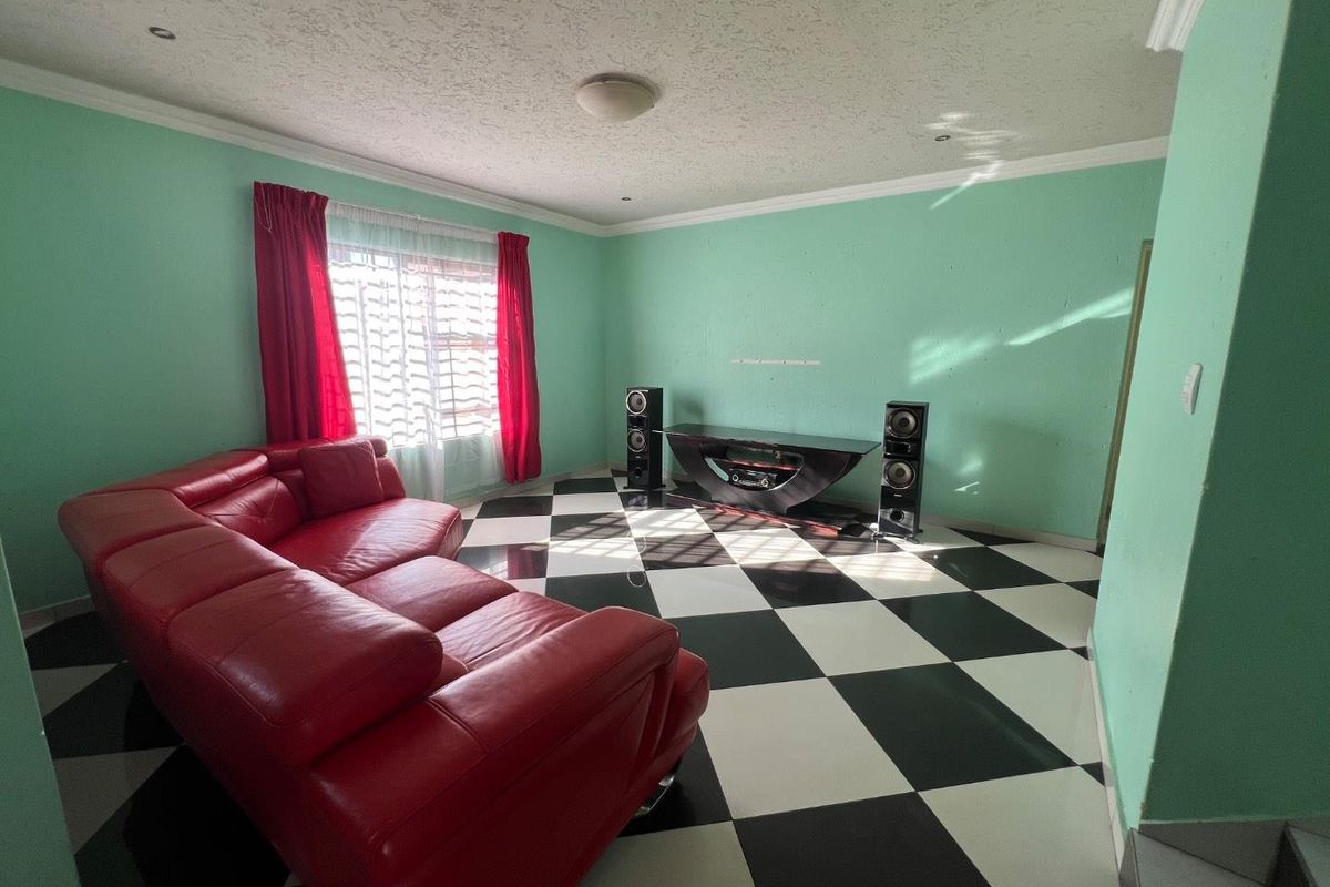 A living room featuring a distinctive checkered tile floor, coved cornicing, and recessed lighting, offering a blank canvas for modern interior updates.