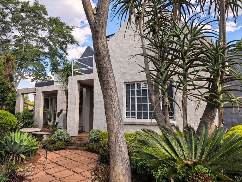 A charming house exterior featuring a textured facade, grid-pattern windows, and a stone-paved walkway leading to a covered entrance porch.