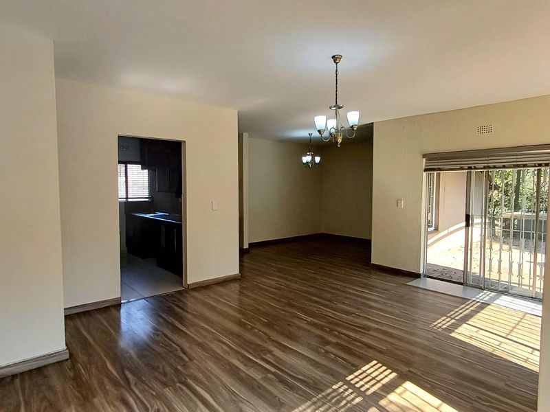 Spacious open-plan living and dining area featuring modern laminate flooring, natural light, and direct access to the outdoor patio through sliding glass doors.