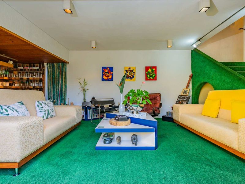 A living room featuring green carpeting, recessed ceiling lighting, and a unique staircase design with built-in shelving.