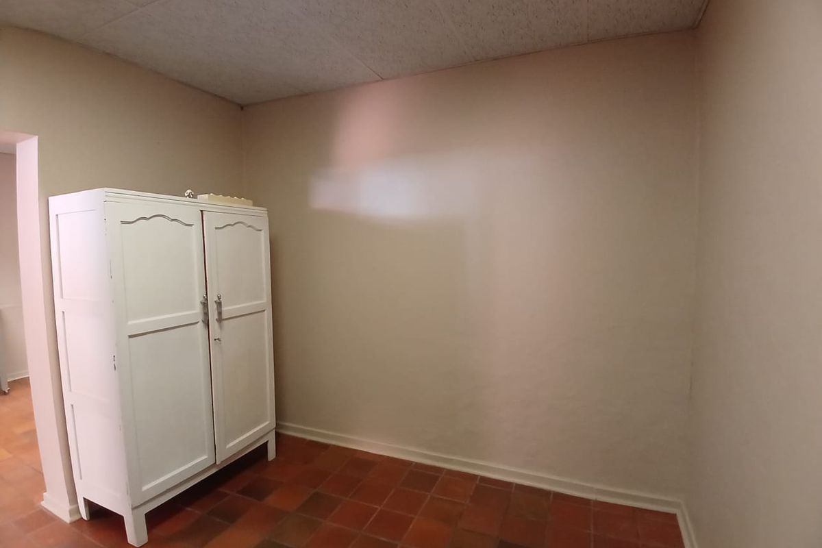 A small, empty room featuring terracotta-style floor tiles and a drop ceiling, offering a blank canvas for potential renovation or repurposing.