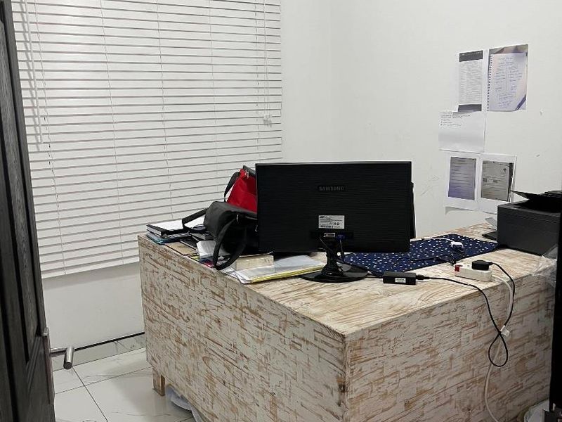 A functional home office space featuring white tiled flooring and fitted venetian blinds, providing a clean and practical workspace.