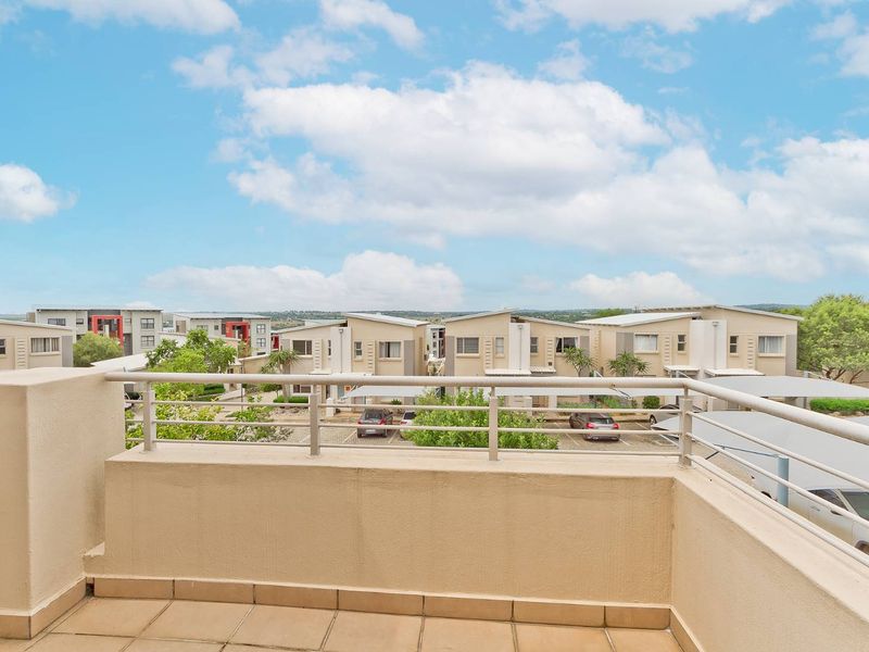 A clean, well-maintained balcony featuring tiled flooring and a metal balustrade, offering an open view of the surrounding residential complex.