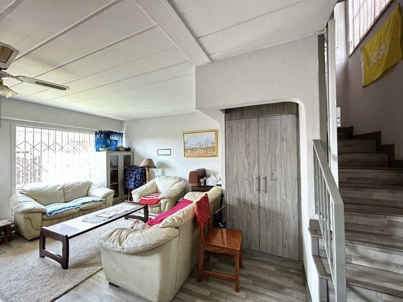 Living room featuring laminate flooring, a built-in storage cupboard, and a staircase leading to the upper level.