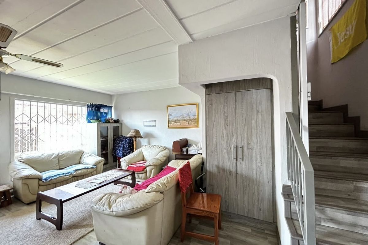 Living room featuring laminate flooring, a built-in storage cupboard, and a staircase leading to the upper level.
