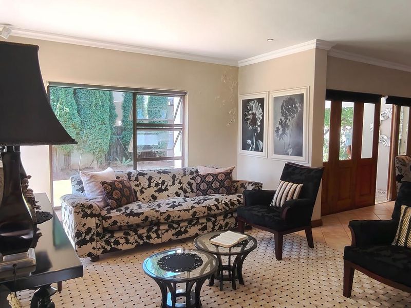 Spacious living room featuring tiled flooring, recessed downlighting, and large windows providing natural light, with direct access through wooden double doors.