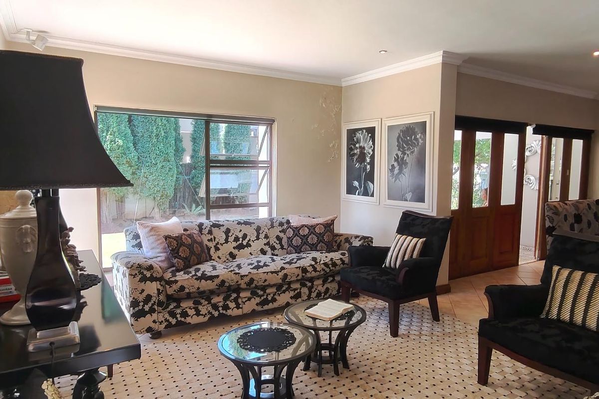 Spacious living room featuring tiled flooring, recessed downlighting, and large windows providing natural light, with direct access through wooden double doors.