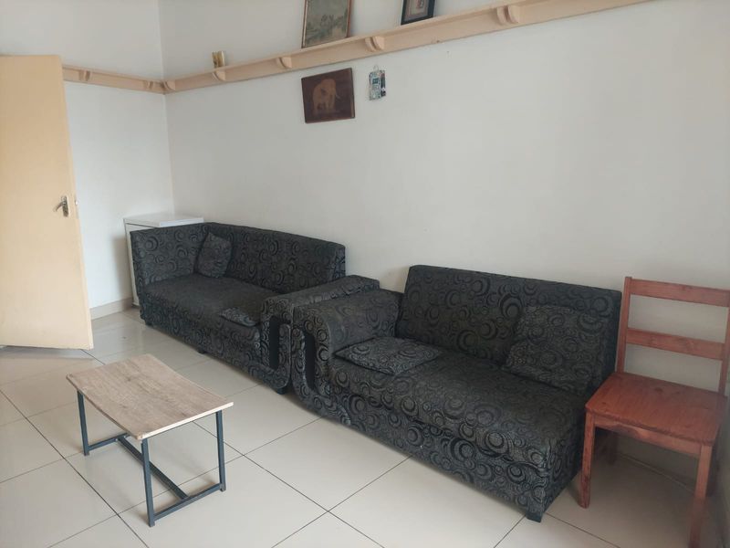 A living room area featuring tiled flooring and a wall-mounted wooden display shelf.