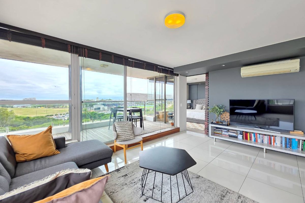 Modern open-plan living area featuring polished tile flooring, split-system air conditioning, and expansive floor-to-ceiling glass doors leading to a private balcony with scenic views.