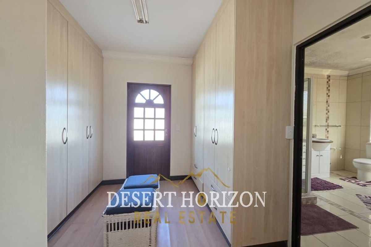 A dressing area featuring extensive built-in floor-to-ceiling cabinetry, providing ample storage space, with direct access to an adjoining bathroom.