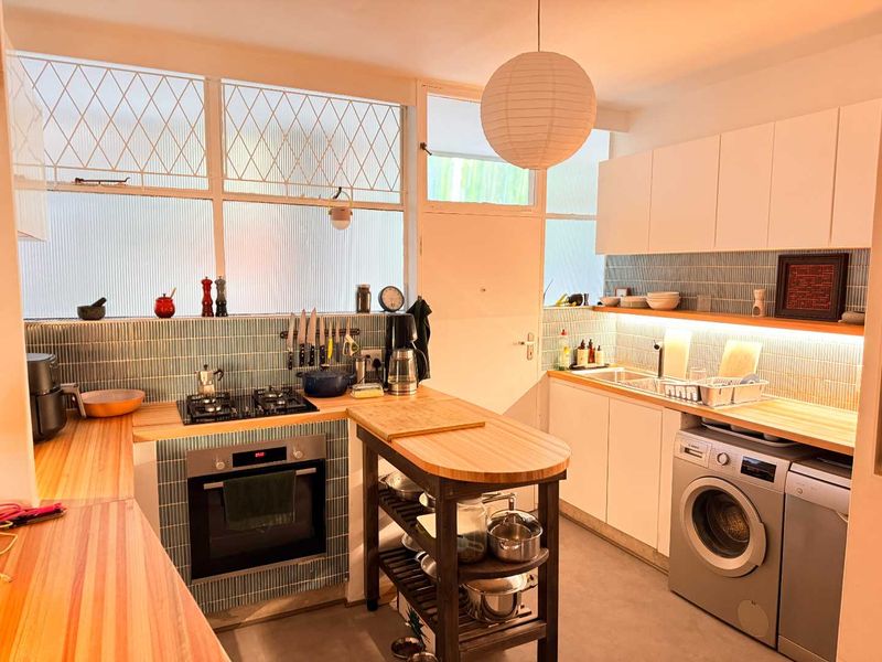 A well-appointed kitchen featuring wooden countertops, a gas hob, built-in oven, tiled backsplash, and integrated cabinetry with under-cabinet lighting.