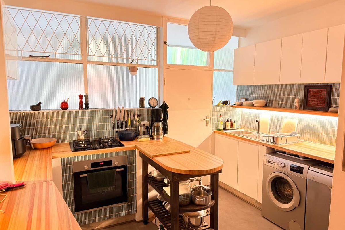 A well-appointed kitchen featuring wooden countertops, a gas hob, built-in oven, tiled backsplash, and integrated cabinetry with under-cabinet lighting.