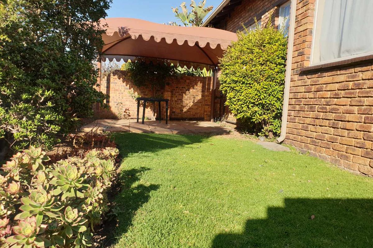 A private rear garden featuring a paved patio area with a fixed fabric gazebo, brick boundary walls, and established lawn.