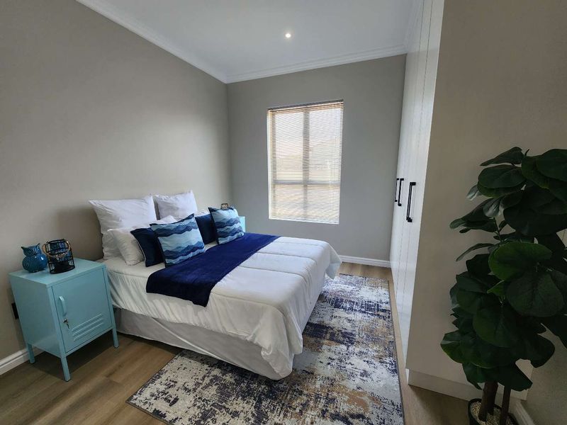 A well-maintained bedroom featuring modern laminate flooring, built-in cupboards, and neutral wall tones, providing a clean and comfortable living space.