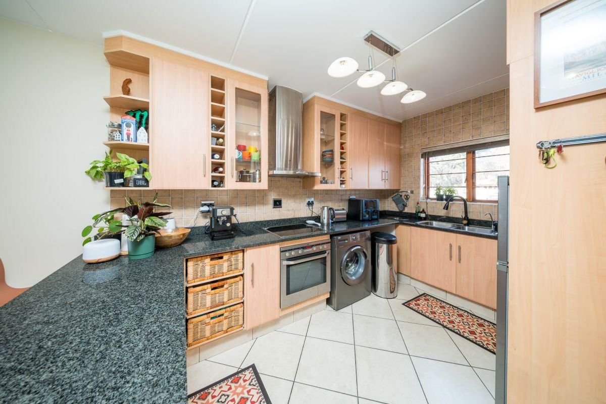 A functional kitchen featuring light wood cabinetry, granite countertops, a tiled backsplash, and integrated appliances including an oven and hob.