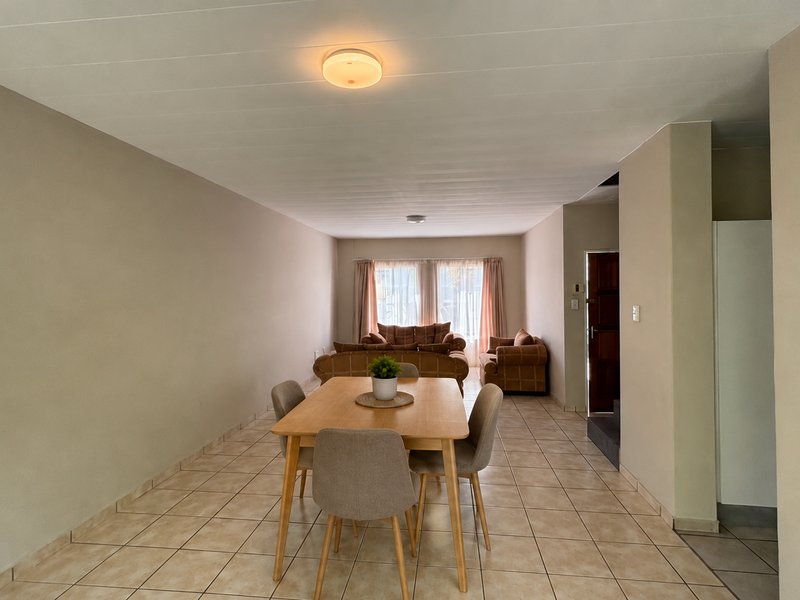 An open-plan living and dining area featuring neutral wall tones, tiled flooring, and a functional layout suitable for modern living.