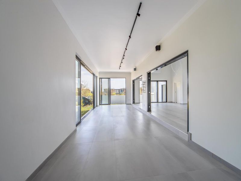 Spacious, modern living area featuring large format floor tiles, track lighting, and expansive sliding glass doors that provide abundant natural light.